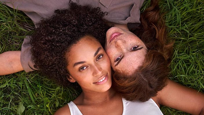 Two women lying on grass looking up.